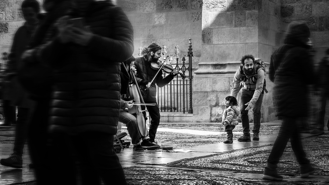 People playing a violin and cello in a public walkway