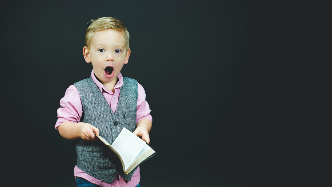 Young boy holding a Bible with a surprised look