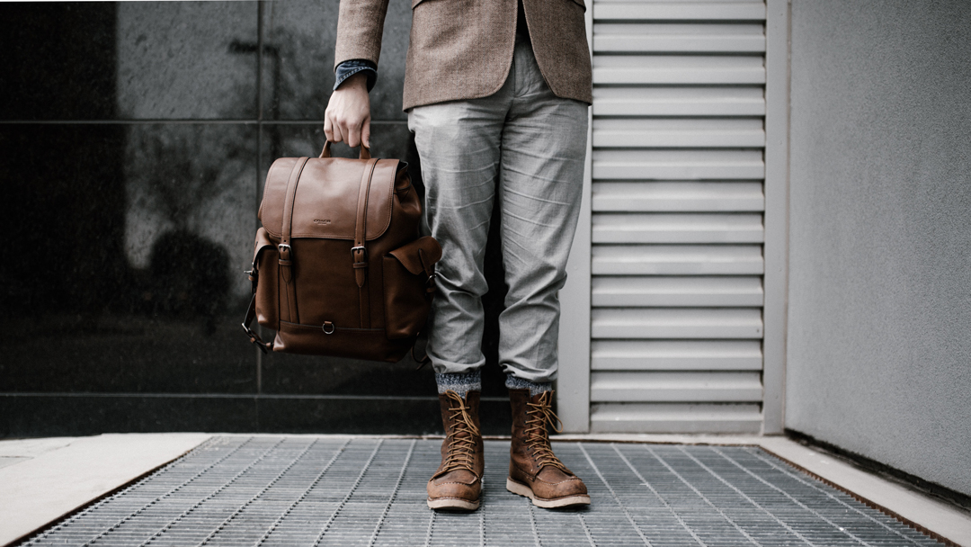 Man holding a leather backpack