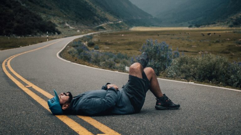Man laying in the middle of an empty road