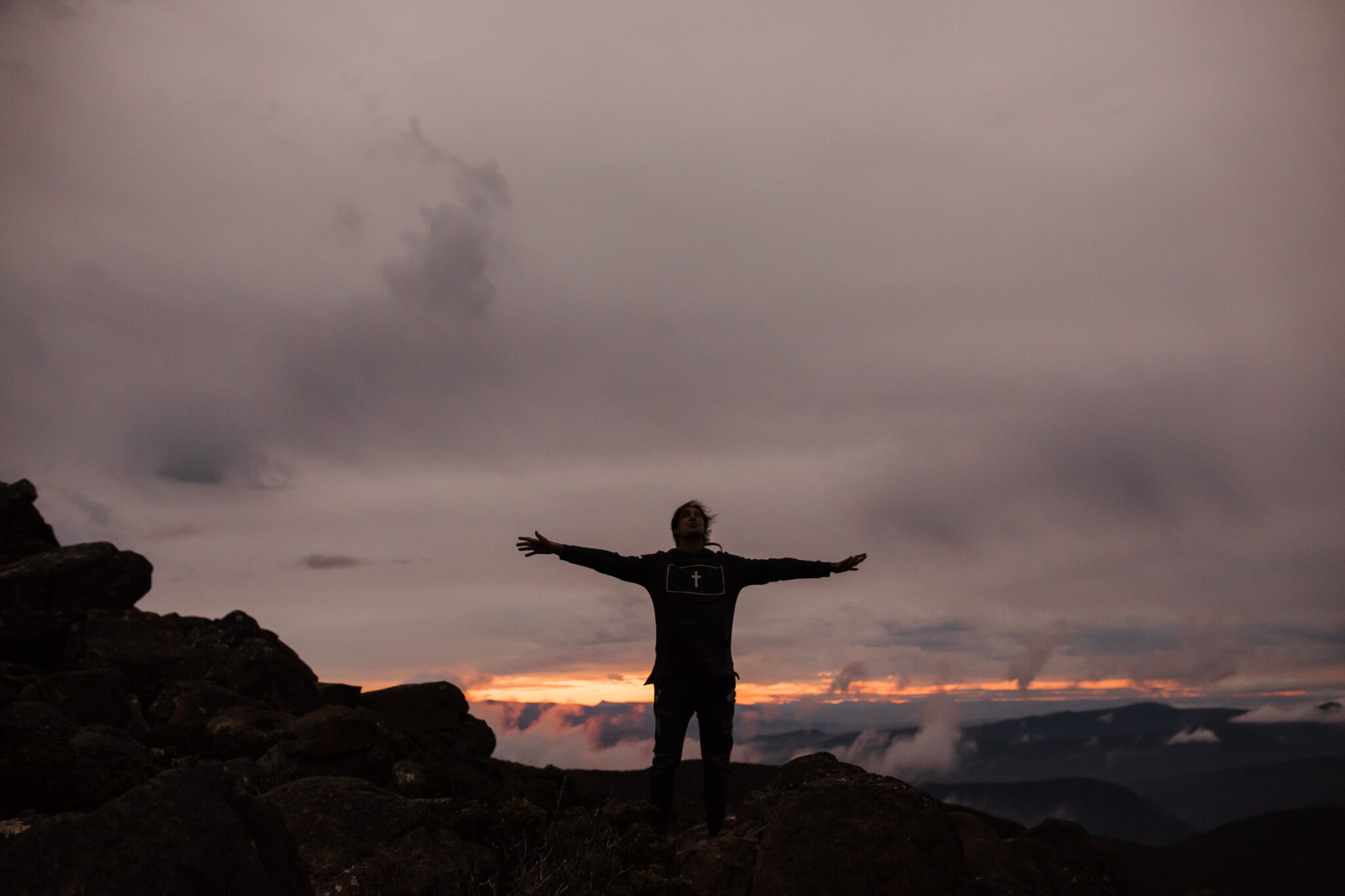 Man holding his hands out on top of a mountain