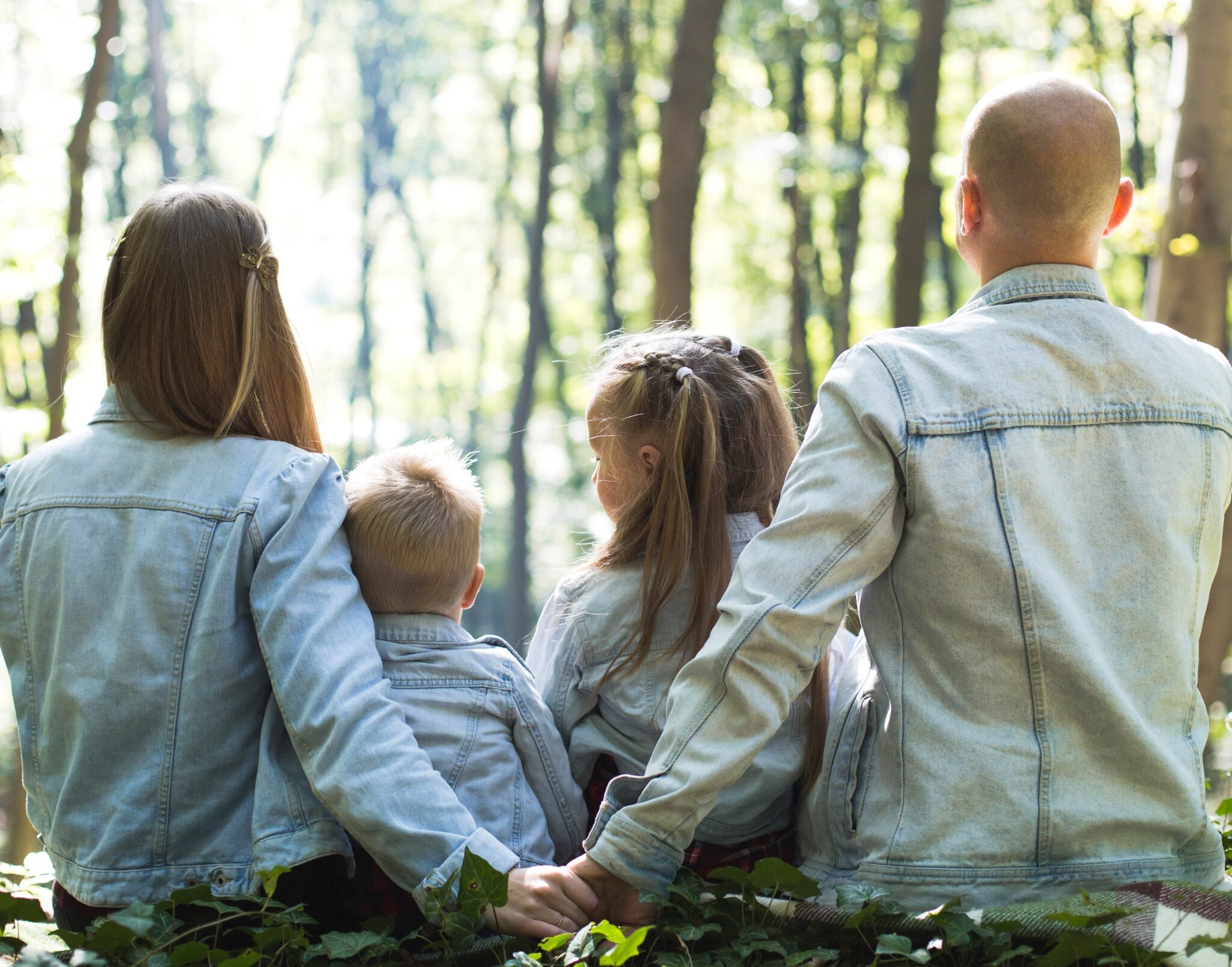 Family of four sitting together in the woods