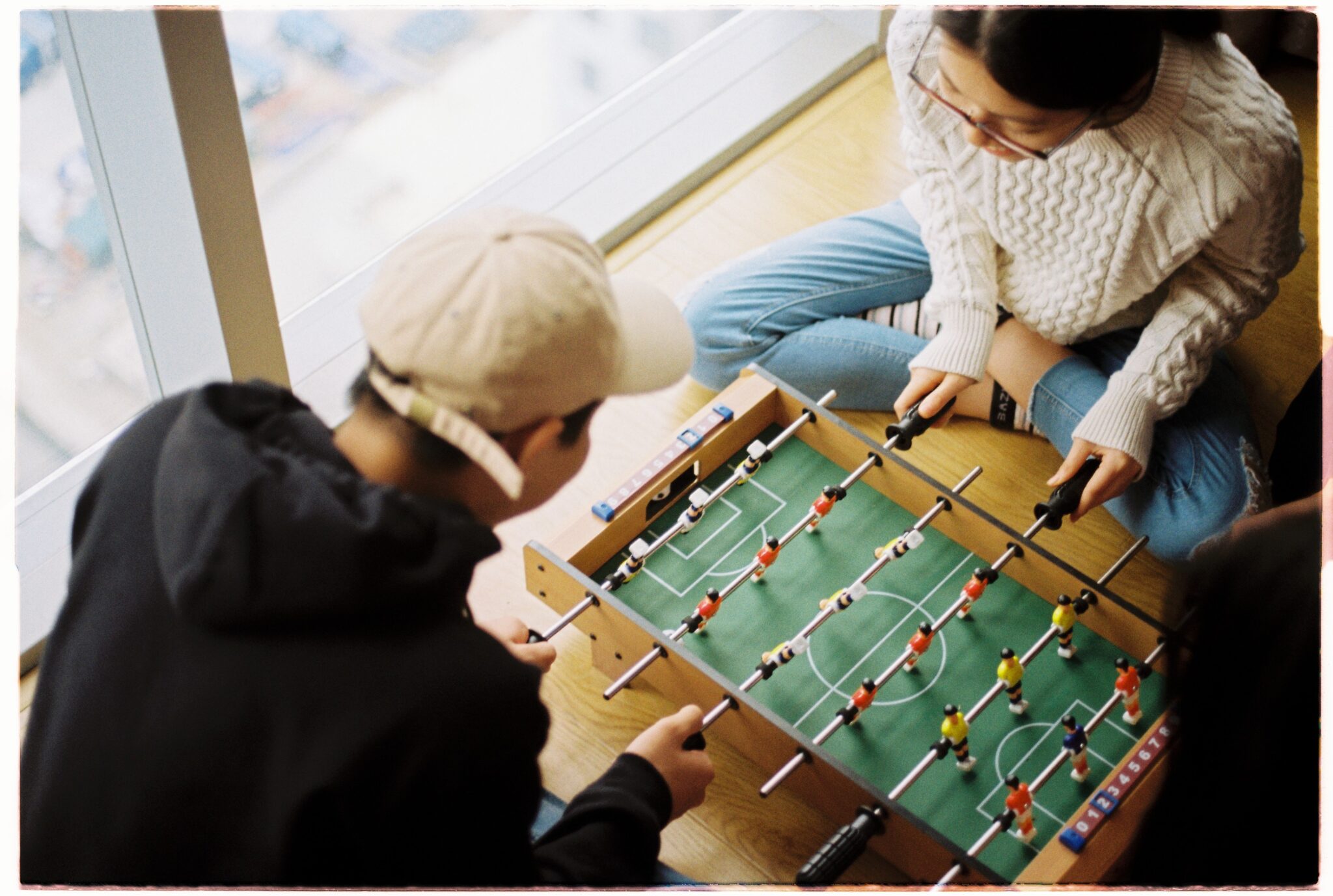 Two people playing foosball on a mini table