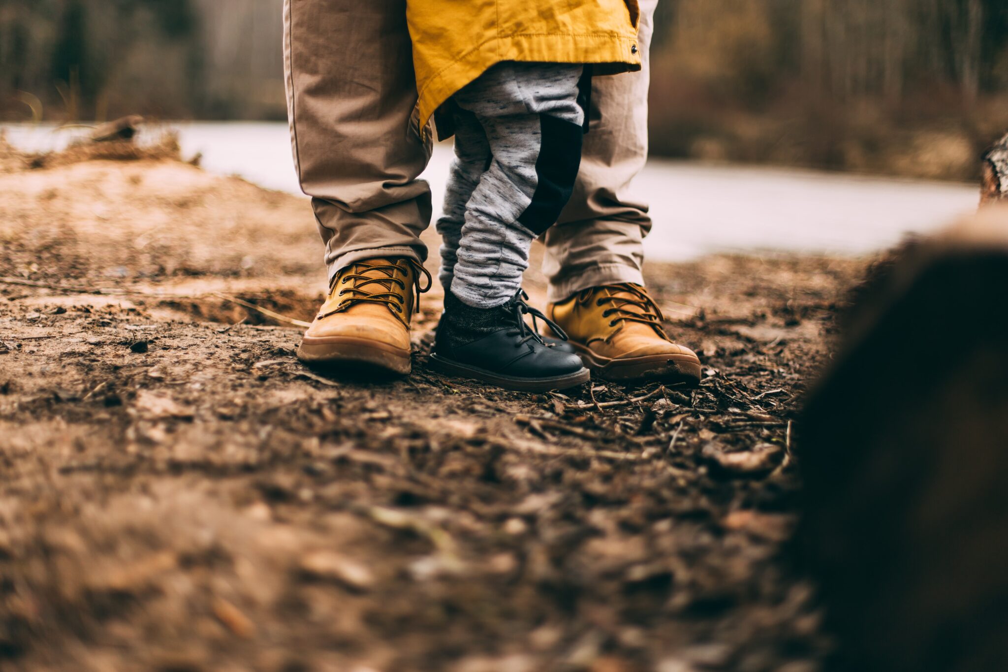 Adult and little kid walking on a dirt trail