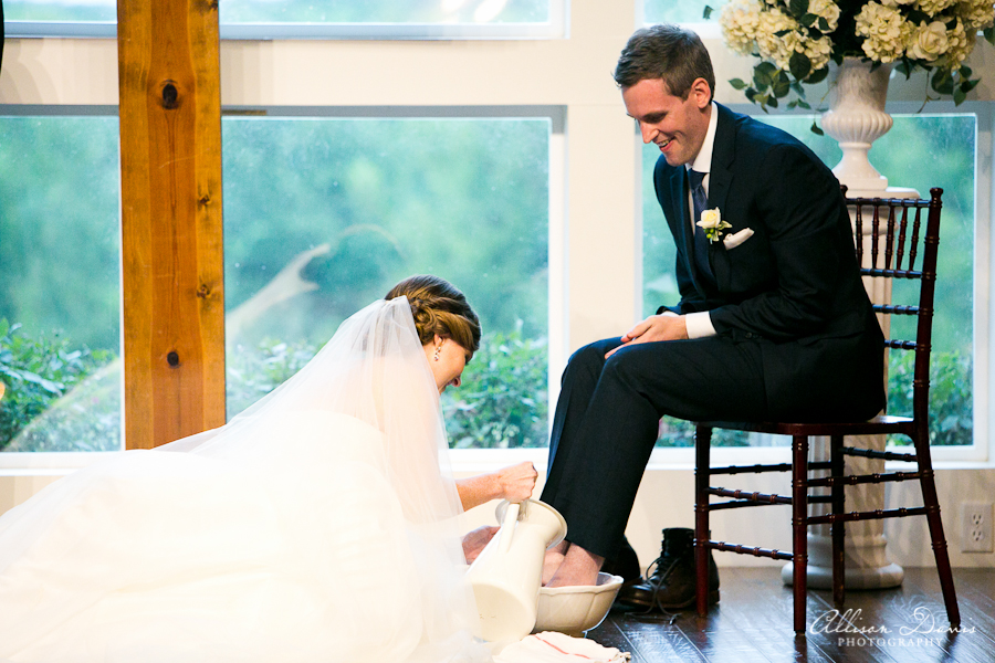 Woman washing mans feet during wedding