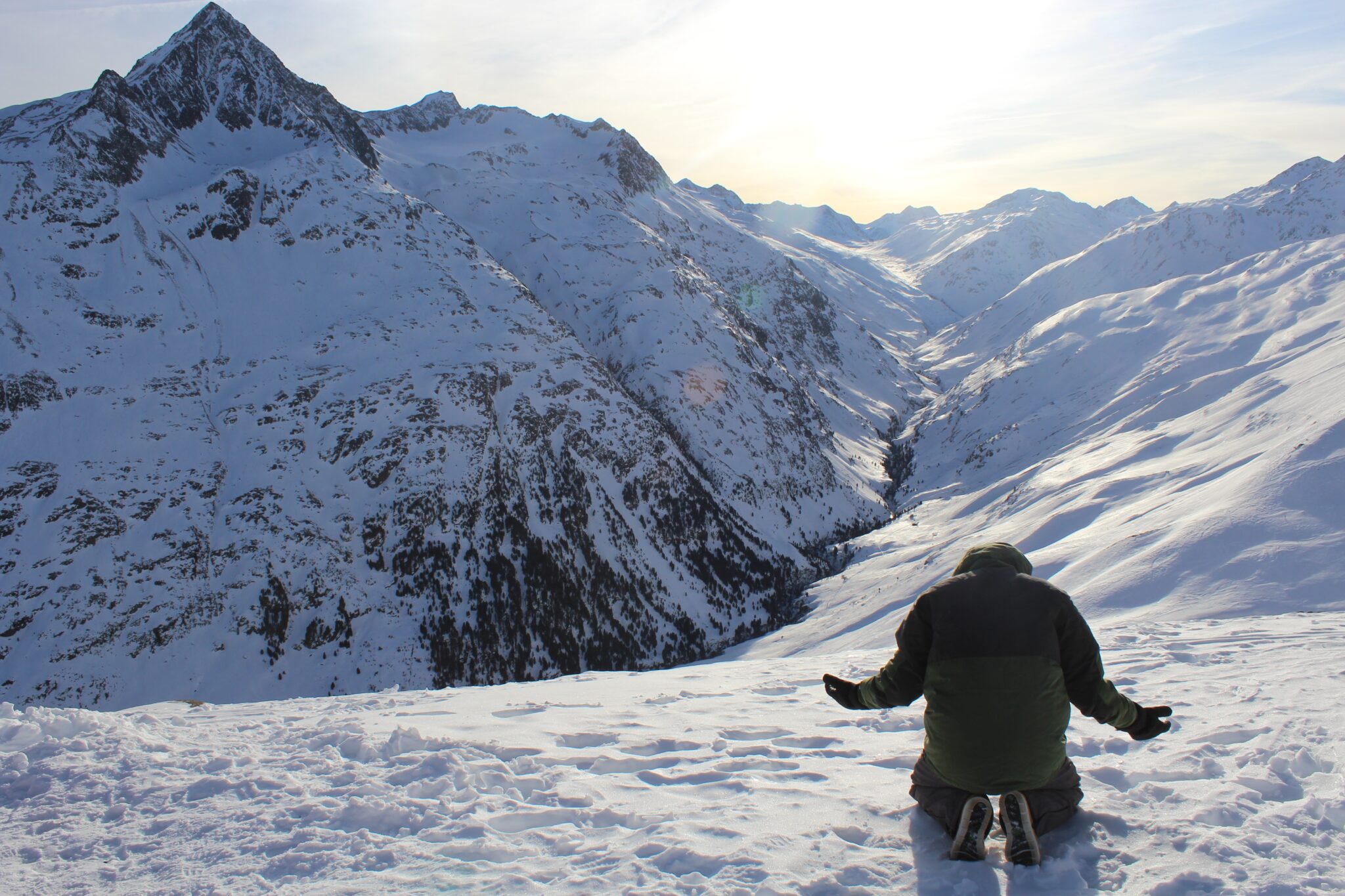 Man praying on top of a snowy mountain