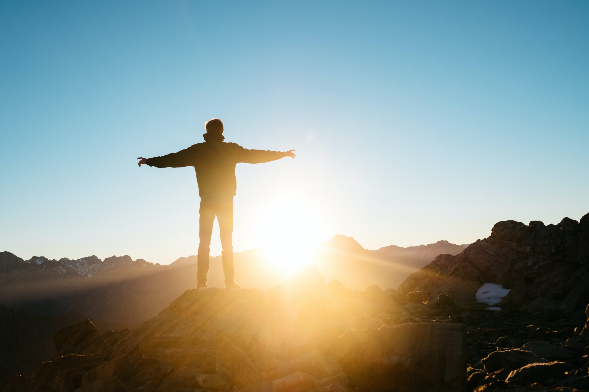 Man on top of a mountain with his arms out wide