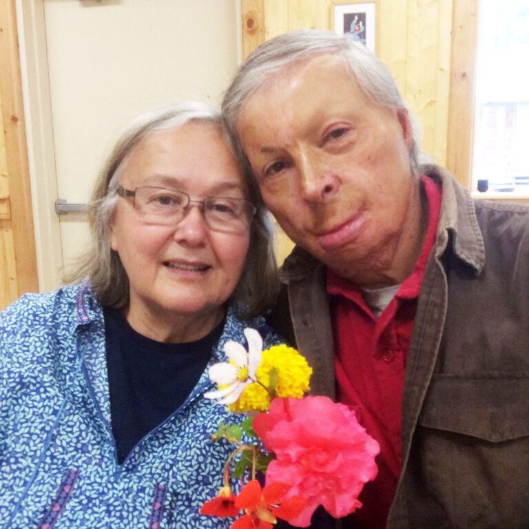 Older couple smiling while holding flowers